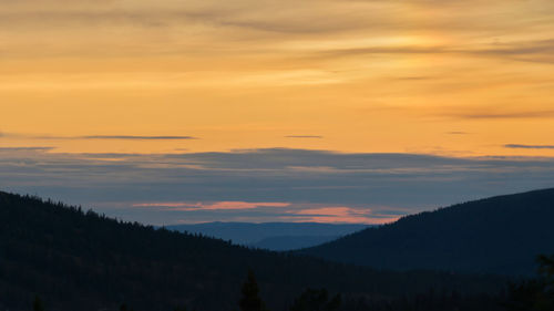 Scenic view of silhouette mountains against orange sky