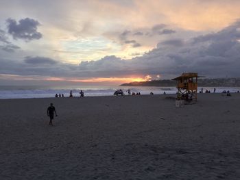 People on beach against sky during sunset