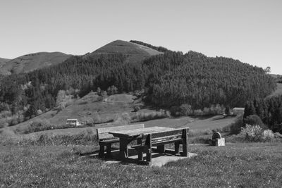 Empty bench on field against clear sky