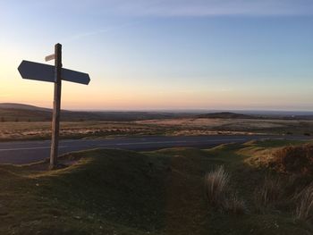 Road sign on countryside landscape at sunset