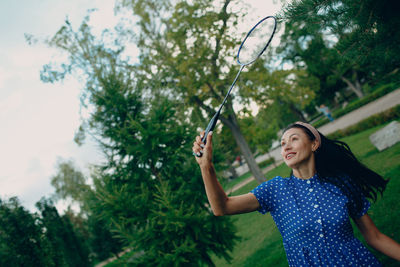 Woman standing by tree against plants