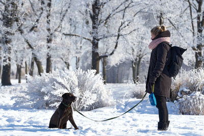 Side view of people and dog standing on snow covered trees