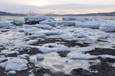 Chunks of ice on the st. lawrence river shore with the pierre-laporte and quebec bridges in winter 