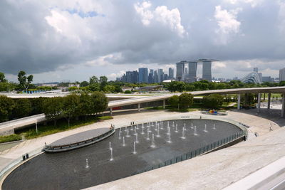 Bridge over river by buildings in city against sky