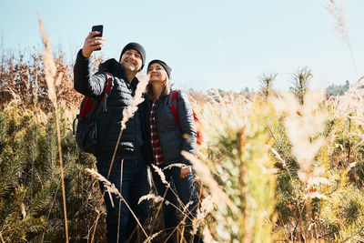 Hugging couple taking selfie while trip. hikers with backpacks. leisure time close to nature