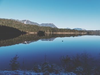 Scenic view of lake and mountains against clear blue sky