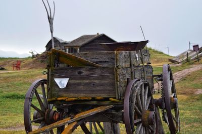 Abandoned cart on field against sky