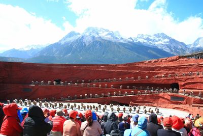 Group of people on snowcapped mountain against sky