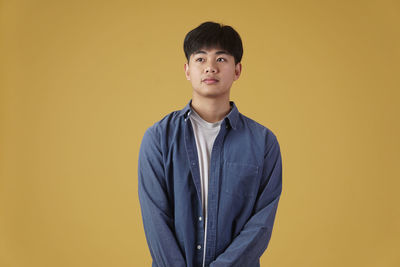 Portrait of boy standing against yellow background