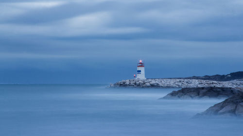 Lighthouse by sea against sky