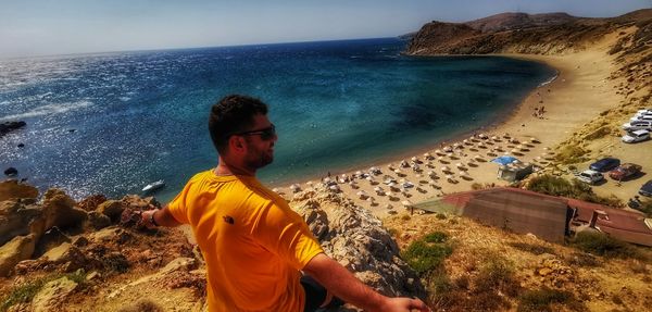 Young man looking at sea against sky