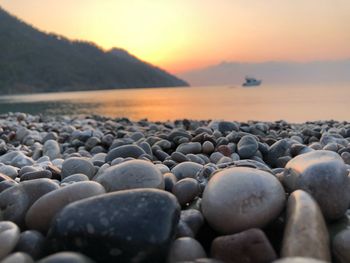 Rocks on beach against sky during sunset