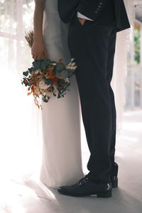 Low section of woman holding bouquet