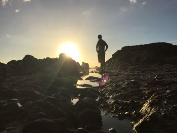 Man standing by sea against sky during sunset