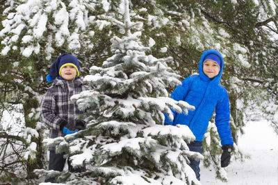 Rear view of boys on snow covered trees during winter