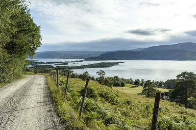 Scenic view of road by mountains against sky