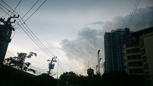 Low angle view of electricity pylon against cloudy sky