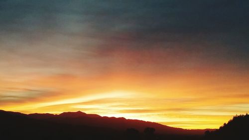 Scenic view of silhouette mountains against orange sky