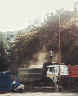 Rear view of man working against sky in city