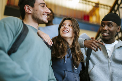 Portrait of smiling friends standing against wall