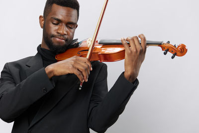 Midsection of man playing violin against white background