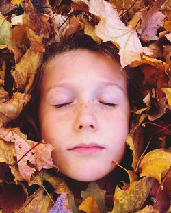 Close-up portrait of boy on dry leaves during autumn