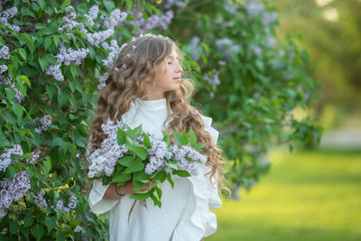 Rear view of woman standing by flowering plants