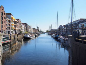 Sailboats moored in harbor against clear sky