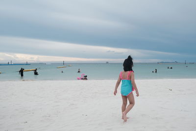 Rear view of women on beach against sky