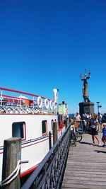 Statue of people on bridge against blue sky