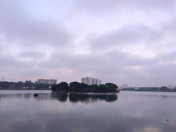 City at waterfront against cloudy sky