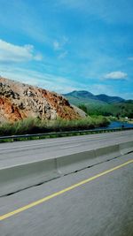 Road by mountains against sky