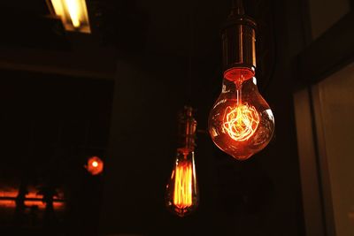 Low angle view of illuminated light bulbs hanging at home