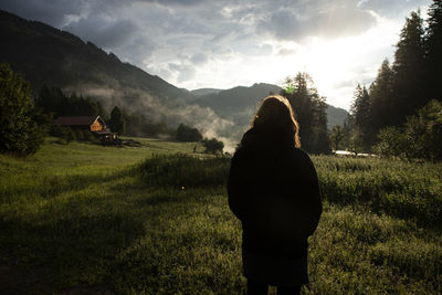 Rear view of woman standing on field during sunrise in austria