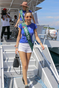 Portrait of smiling young woman standing on boat