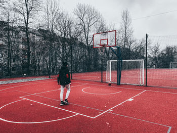 Rear view of man with basketball hoop against sky