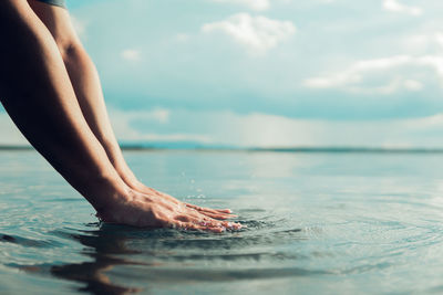 Low section of person in sea against sky