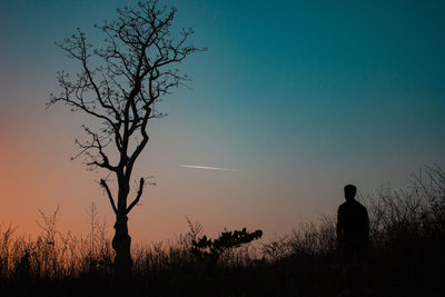 Silhouette man standing on field against sky during sunset