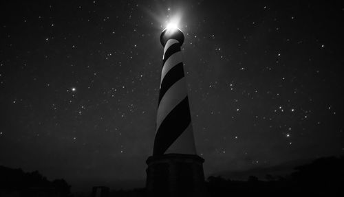 Low angle view of illuminated sign against sky at night