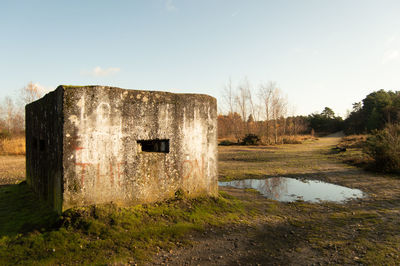 Old ruin on field by lake against sky