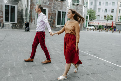 Full length of friends standing on footpath in city