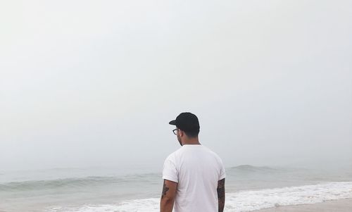Rear view of man looking at sea against clear sky