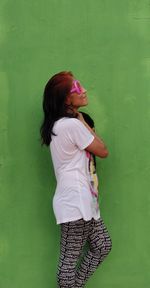 Side view of woman standing against pink wall