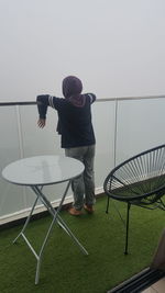 Rear view of man standing by railing fog outdoors outside 