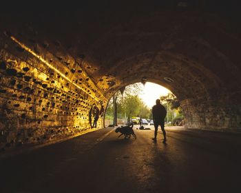 Silhouette people walking in tunnel