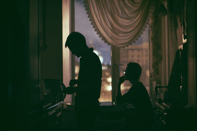 Silhouette men standing by window