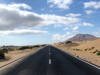 Road leading towards mountains against sky