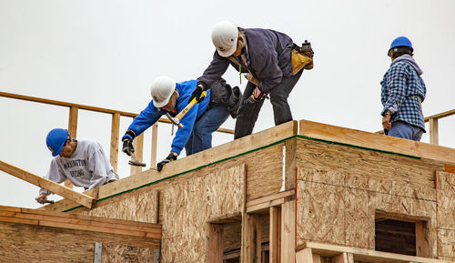 Low angle view of people working at construction site against sky