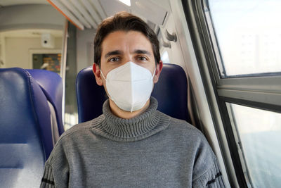Close up of male commuter wearing ffp2 kn95 protective mask on train looking at camera