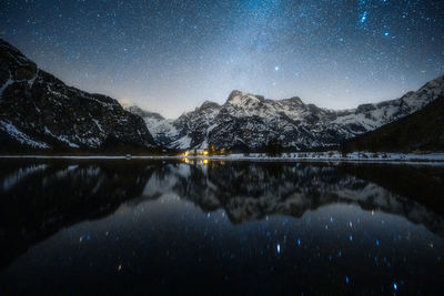 Scenic view of lake and mountains against sky at night